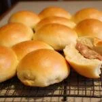 Golden brown brioche hot dog buns cooling on a rack, highlighting their soft and fluffy texture for a delicious finish.