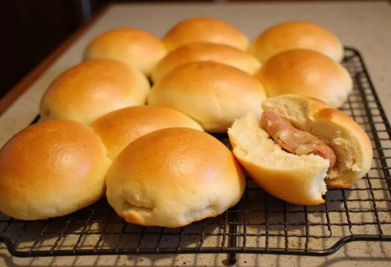 Golden brown brioche hot dog buns cooling on a rack, highlighting their soft and fluffy texture for a delicious finish.