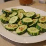 A finished platter of Crisp Hot House Cucumber Bites, featuring vibrant hot house cucumbers topped with a delicious cream cheese spread, perfect for appetizers.
